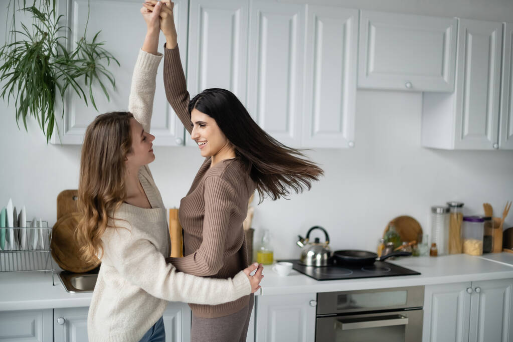 Позитивна лесбійська пара танцює на кухні вдома
  - Фото, зображення