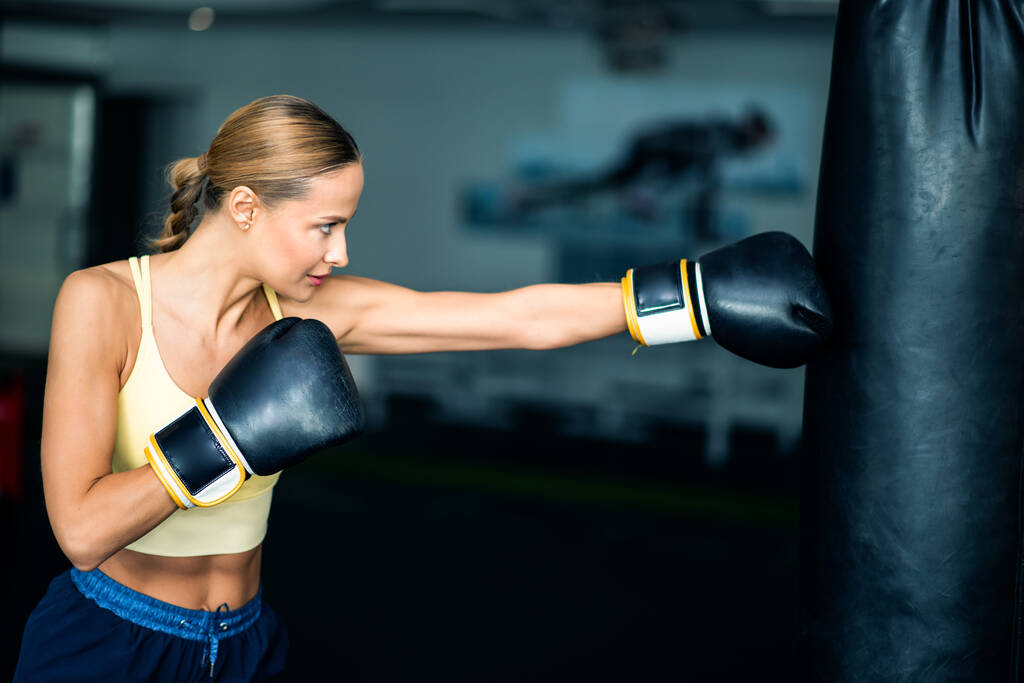 Trening kobiet na worku bokserskim w siłowni, koncepcja fitness - Zdjęcie, obraz