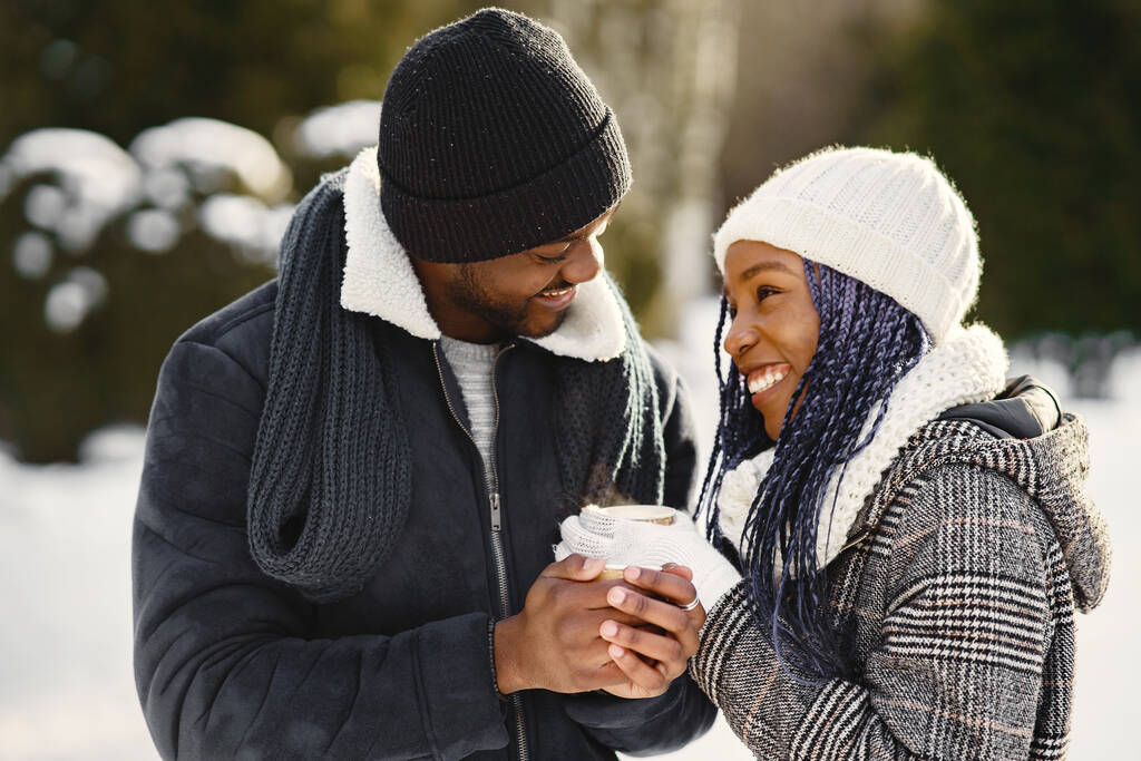 Die Menschen gehen nach draußen. Wintertag. Afrikanisches Paar mit Kaffee. - Foto, Bild