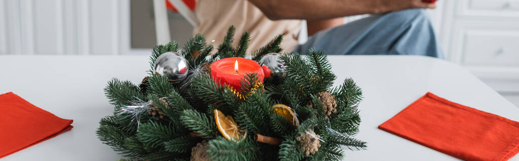 guirnalda de abeto decorado con velas y bolas de Navidad cerca del hombre afroamericano recortado, pancarta - Foto, Imagen