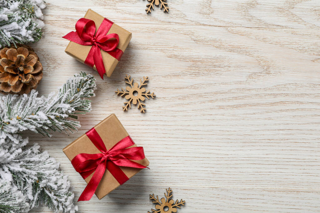 Κουτιά δώρου, κλαδιά ελάτης και χριστουγεννιάτικη διακόσμηση σε λευκό ξύλινο τραπέζι, επίπεδη lay. Χώρος για κείμενο - Φωτογραφία, εικόνα