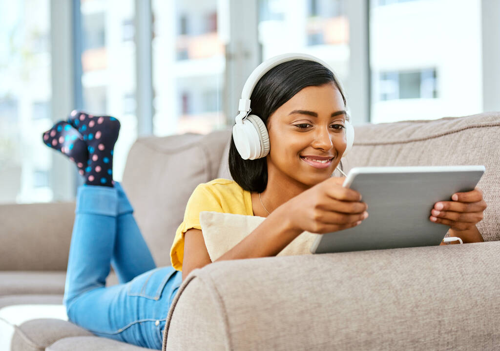 Mijn afspeellijst met een druk op de vinger. een tienermeisje dat thuis naar muziek luistert en een tablet gebruikt - Foto, afbeelding