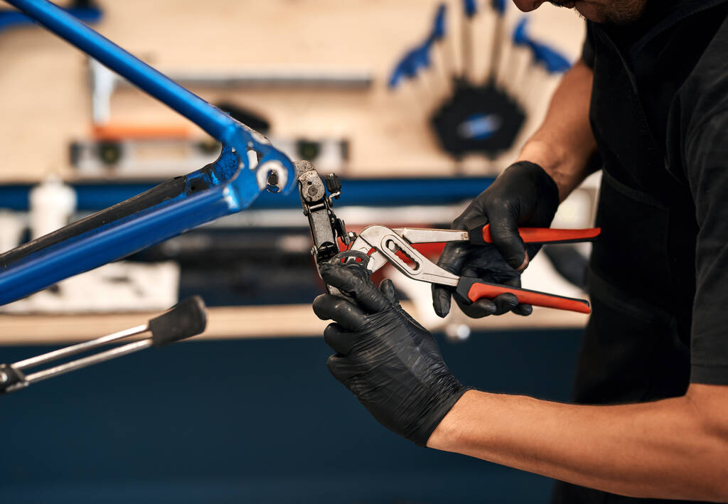 Zostawić rower w wykwalifikowanych rękach. mężczyzna naprawiający rower w warsztacie - Zdjęcie, obraz
