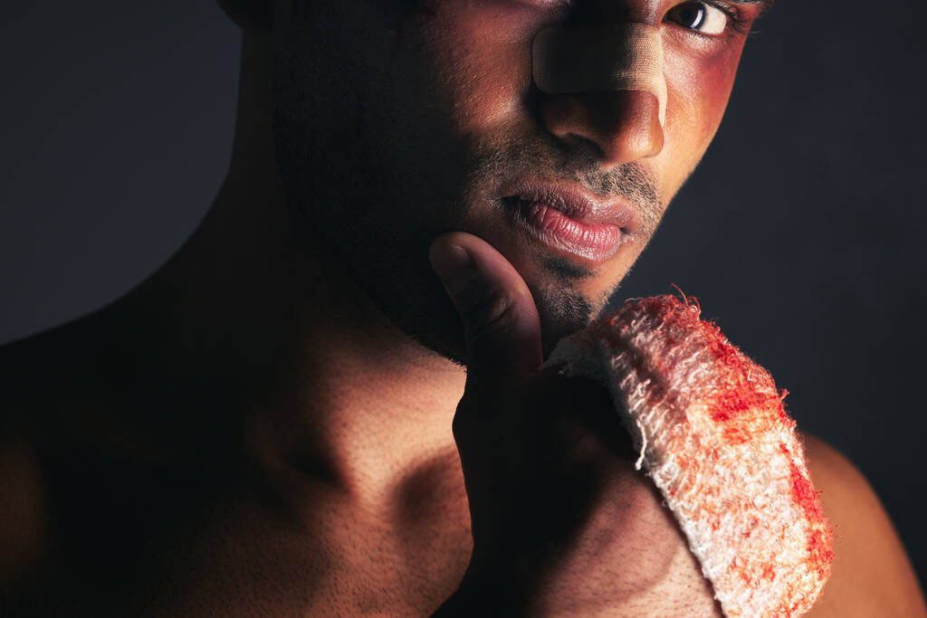 Walka, krew i portret mężczyzny z siniakami na oku, twarzy i zakrwawionymi bandażami. Przemoc, boks i młody bokser z kontuzją, ranami i zranieniem od mma sport na czarnym tle w studio. - Zdjęcie, obraz