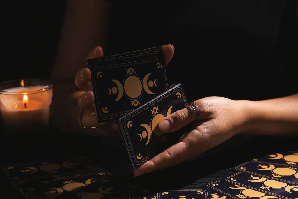 Soothsayer tasuje karty tarota przy stole w ciemności. Przepowiadanie szczęścia - Zdjęcie, obraz