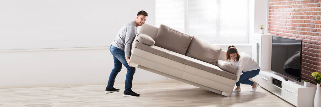 Μετακίνηση νέου καναπέ στο σπίτι. Τοποθέτηση καναπέ κοντά στην τηλεόραση - Φωτογραφία, εικόνα