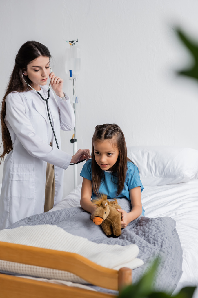 Orvos ellenőrzi a gyermek tüdejét sztetoszkóppal a kórházi kórteremben  - Fotó, kép