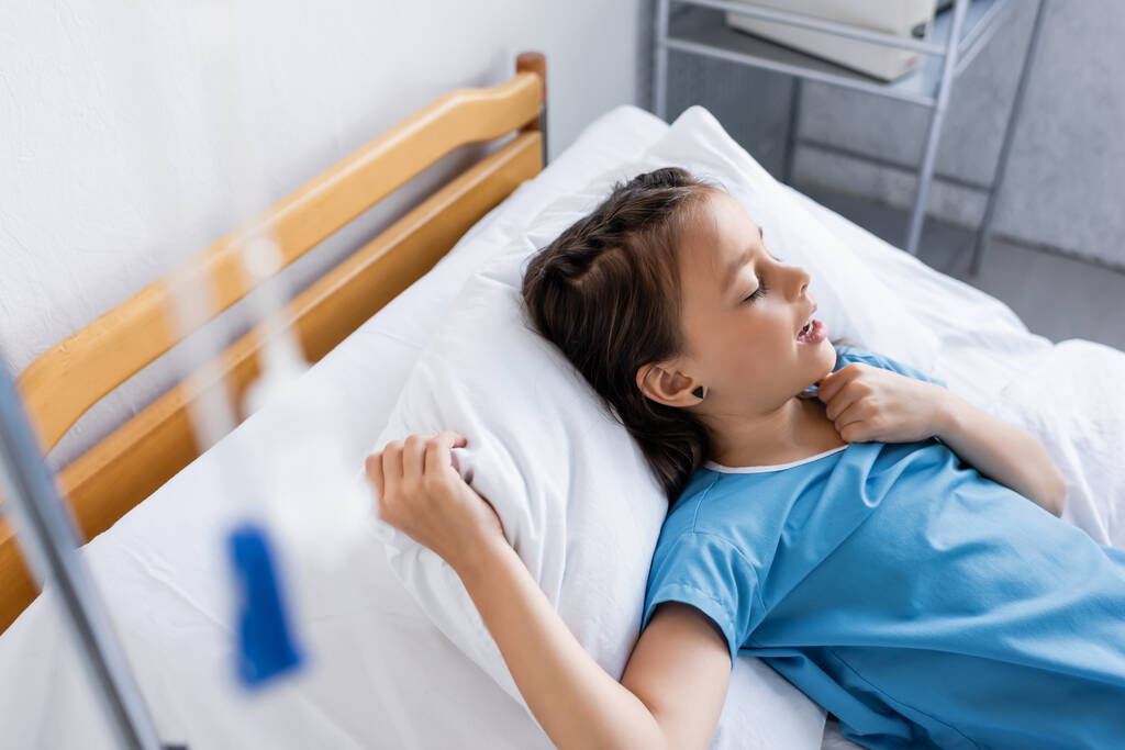 Vista de ángulo alto del niño enfermo acostado en la cama en el hospital  - Foto, imagen