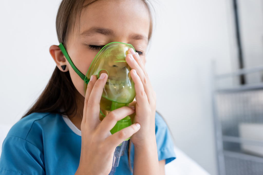Beteg köpenyes gyermek oxigénmaszkkal a klinikán.  - Fotó, kép