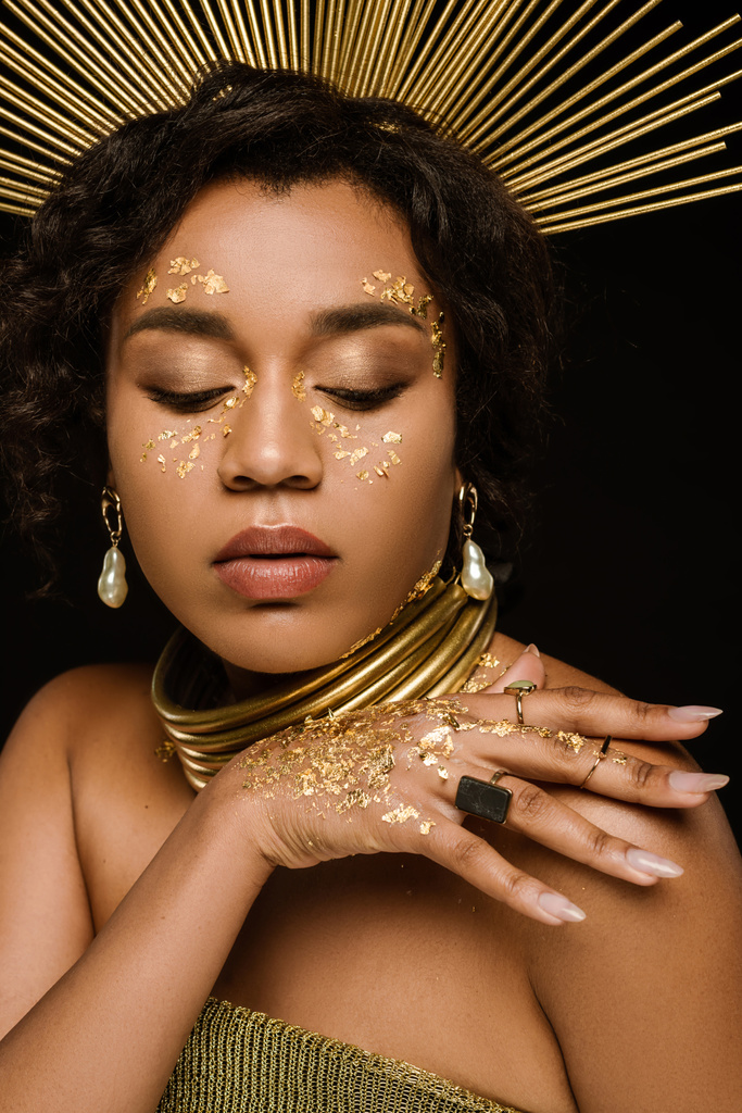 アフリカ系アメリカ人の若い女性で黄金の王冠と黒で隔離された顔にペイント - 写真・画像