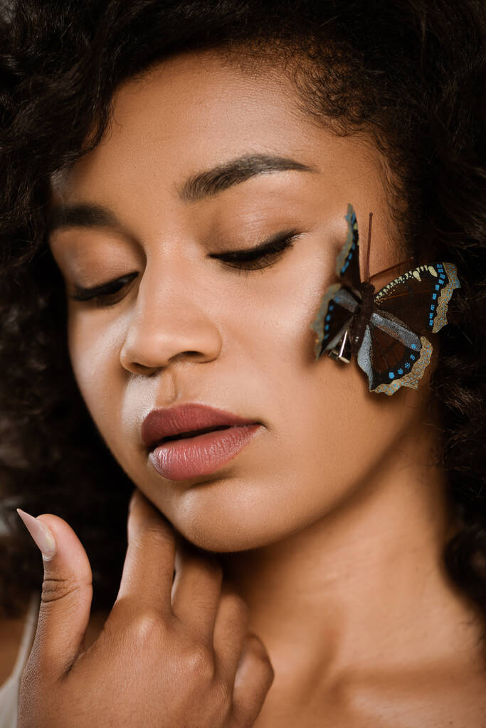 закрыть кудрявую африканскую женщину с бабочкой на лице - Фото, изображение