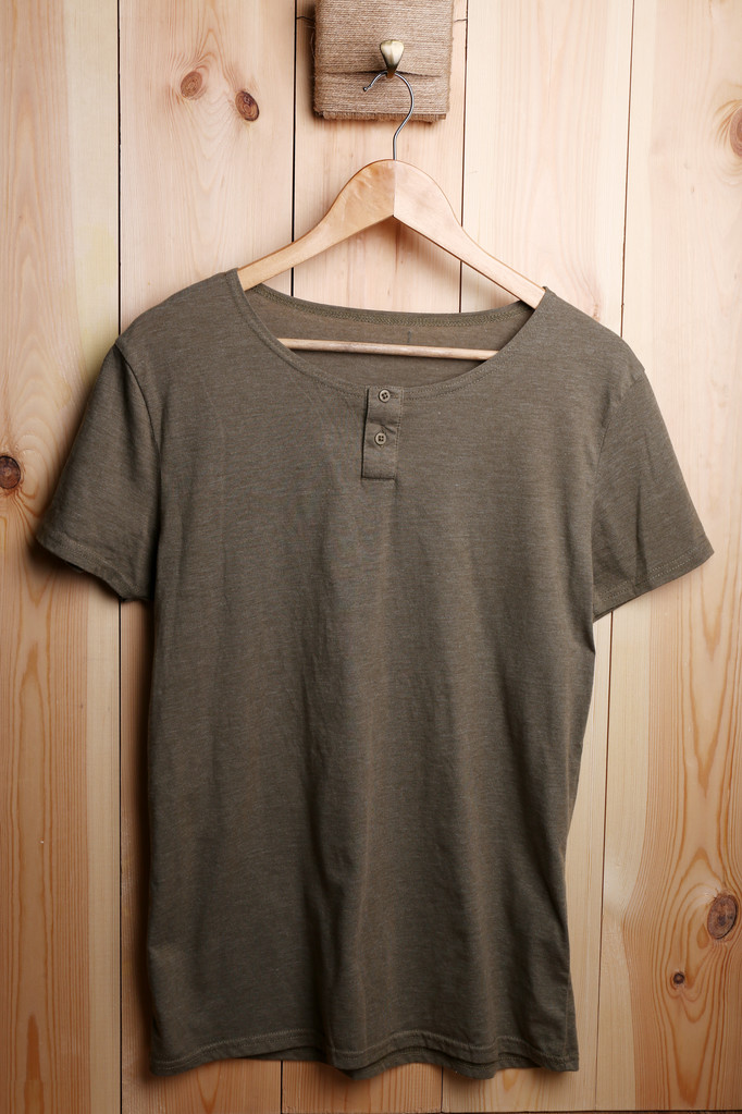 Mannelijke t-shirt op hanger op houten muur achtergrond - Foto, afbeelding