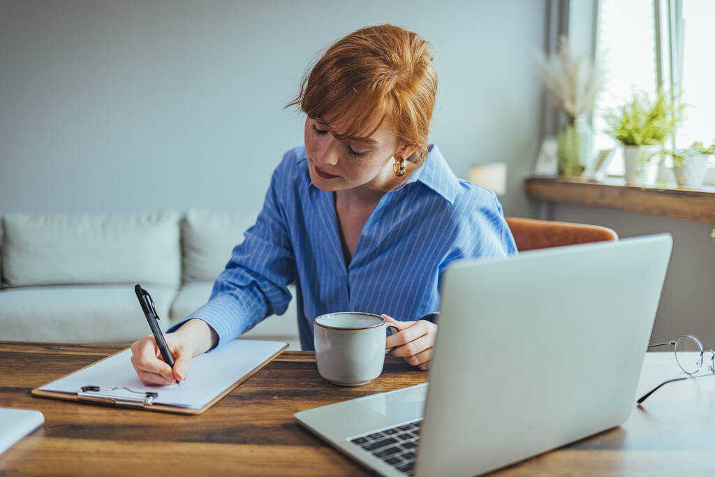 Tyytyväinen nainen kotiäiti lasit istuu pöydässä lähellä laptop tilalla kynä kirjallisesti suunnittelu perheen budjetti muistiinpanoja - Valokuva, kuva