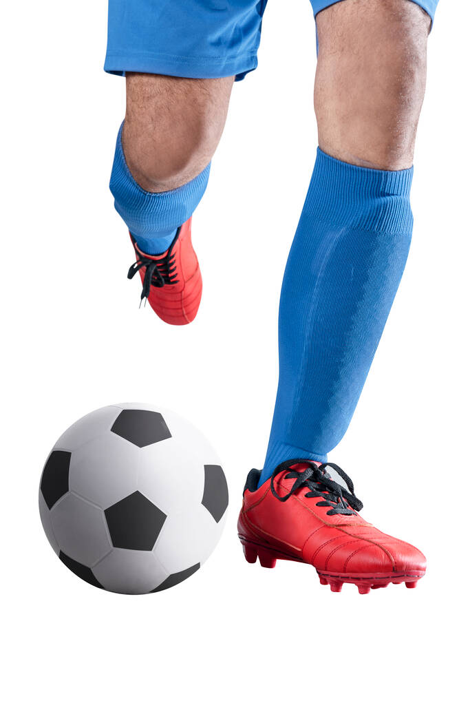 Jalkapalloilija mies sinisessä pelipaidassa potkimassa palloa poseeraten valkoisella taustalla - Valokuva, kuva