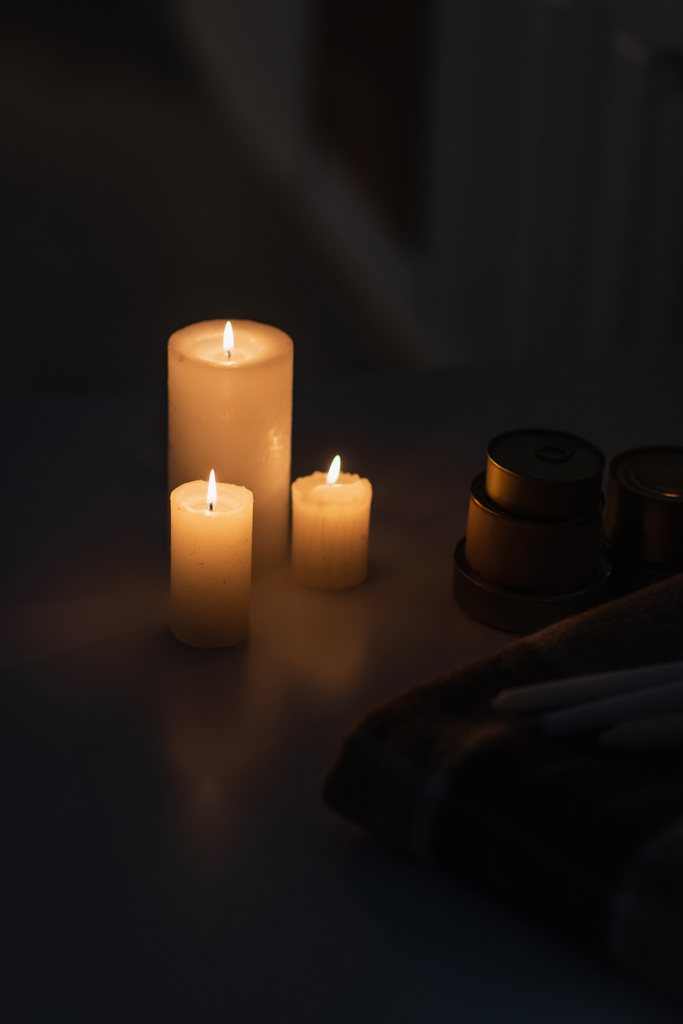 κεριά που καίγονται κοντά σε κονσερβοποιημένα τρόφιμα και ζεστή κουβέρτα κατά τη διακοπή ρεύματος - Φωτογραφία, εικόνα