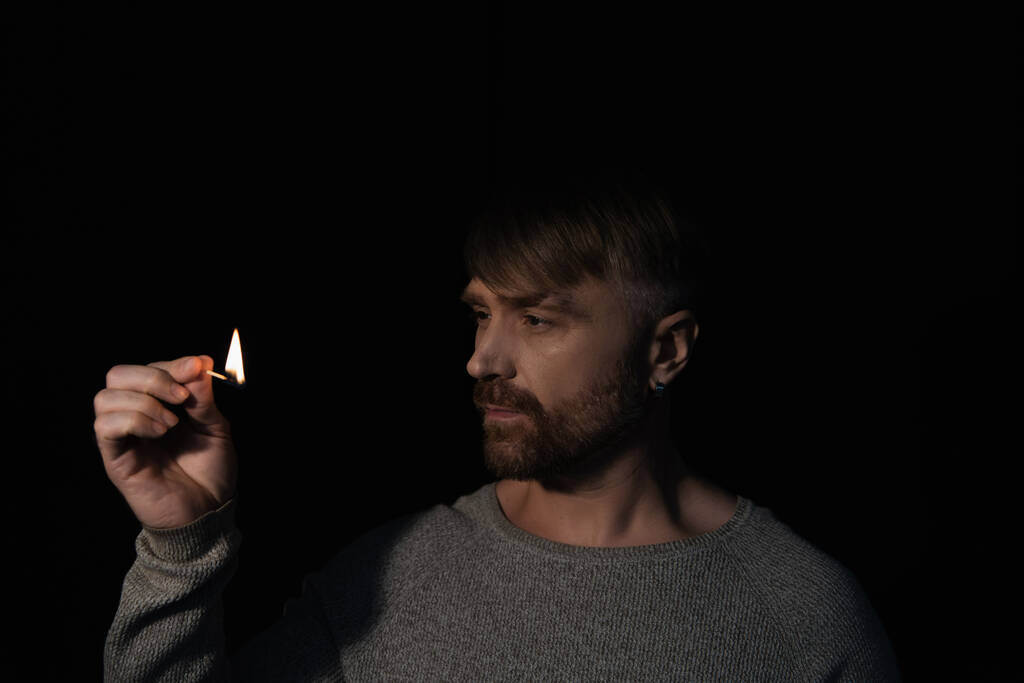 homem olhando para chama de queima jogo na escuridão isolado no preto - Foto, Imagem