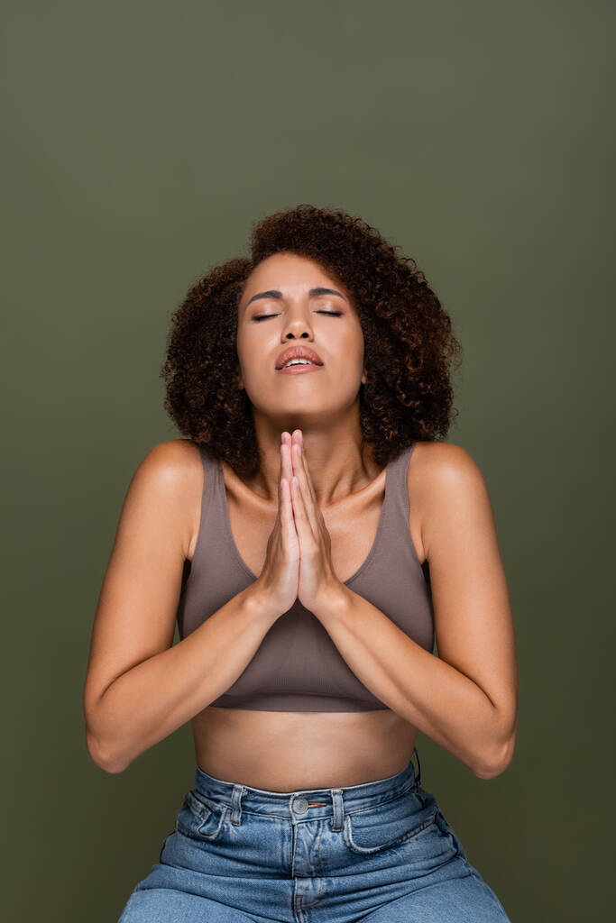 Fiatal afro-amerikai nő a tetején imádkozó kezek és csukott szemmel elszigetelt zöld  - Fotó, kép