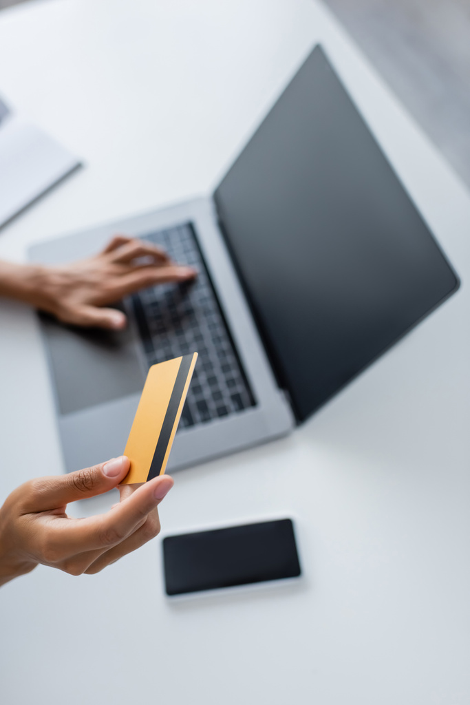 Обрізаний вид афроамериканки, що тримає кредитну картку і використовує ноутбук з порожнім екраном вдома
  - Фото, зображення