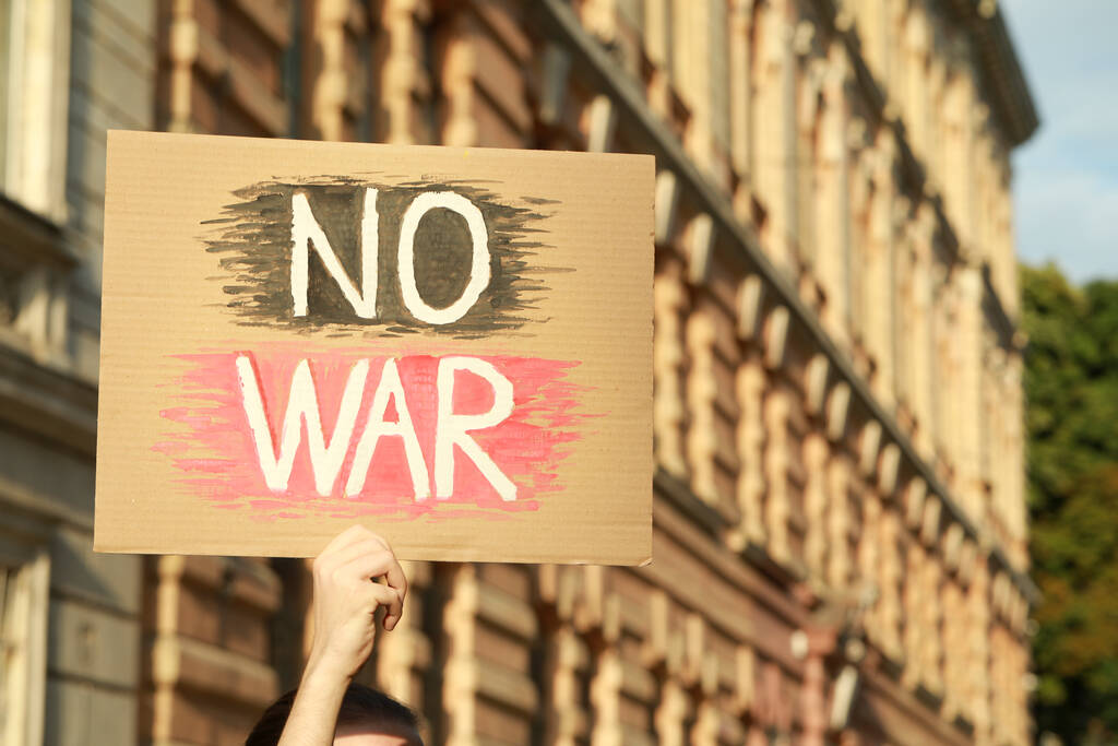 Mulher segurando cartaz com palavras No War ao ar livre. Espaço para texto - Foto, Imagem