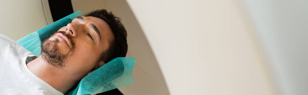 высокий угол обзора бородатого взрослого мужчины, делающего диагностику на КТ сканере в больнице, баннер - Фото, изображение