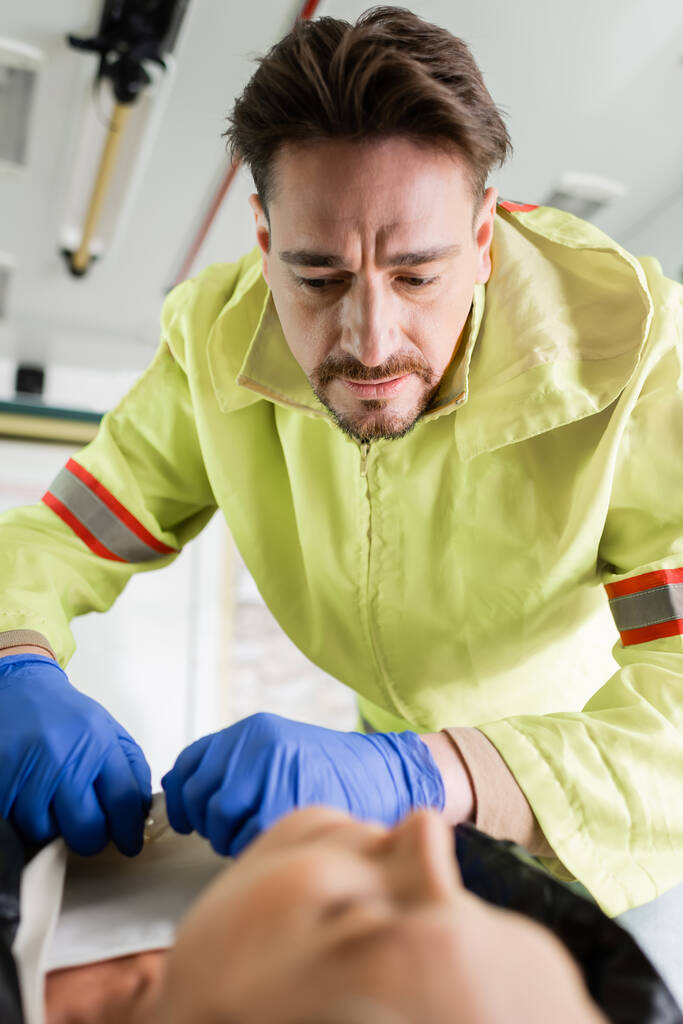 Plastik eldivenli sağlık görevlisi acil servisteki bulanık hastadan giysilerini çıkarıyor.  - Fotoğraf, Görsel