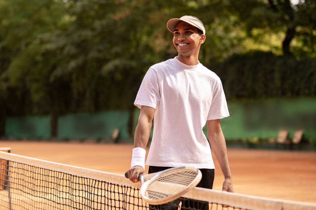 Teniszező. Fiatal férfi fehér pólóban, teniszütővel a kezében. - Fotó, kép