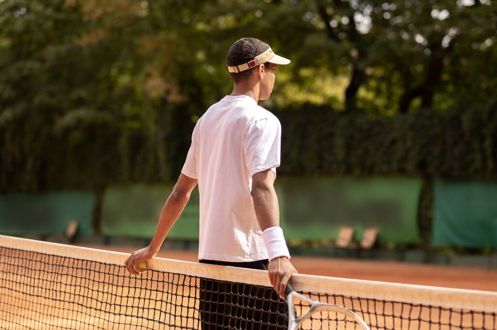 Workout. Young man in sun visor at the tennis courts - Photo, Image