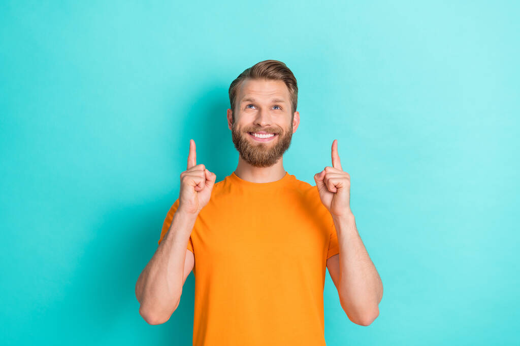 Fotografie veselý optimistický muž s blond účes oblečený oranžové tričko režie vzhled prázdný prostor izolované na pozadí teal barva. - Fotografie, Obrázek