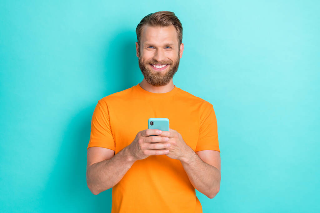 Zdjęcie pozytywnej osoby zębaty uśmiech trzymać używać rozmowy telefoniczne izolowane na turkusowym tle koloru. - Zdjęcie, obraz