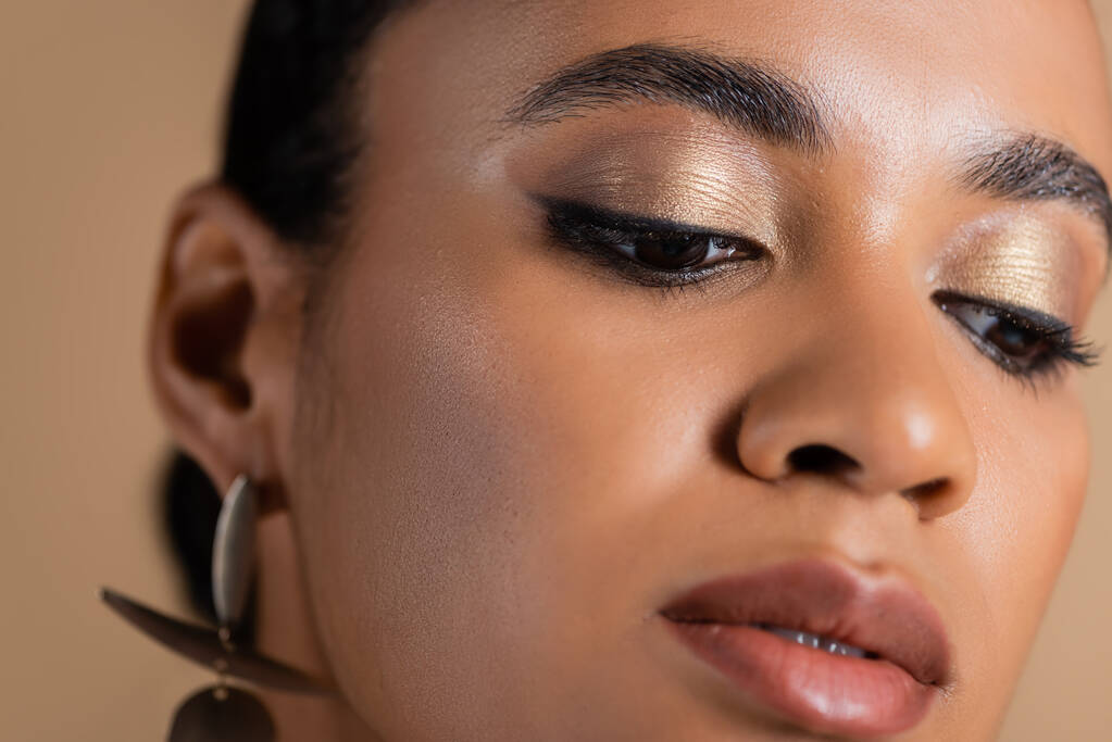 close up of african american woman with golden shimmery eye shadow isolated on beige - Photo, Image