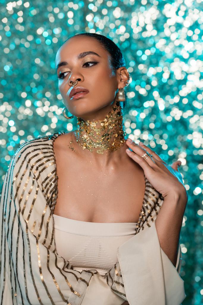 sensual african american woman with shiny shawl and gold on neck posing on sparkling blue background  - Photo, Image
