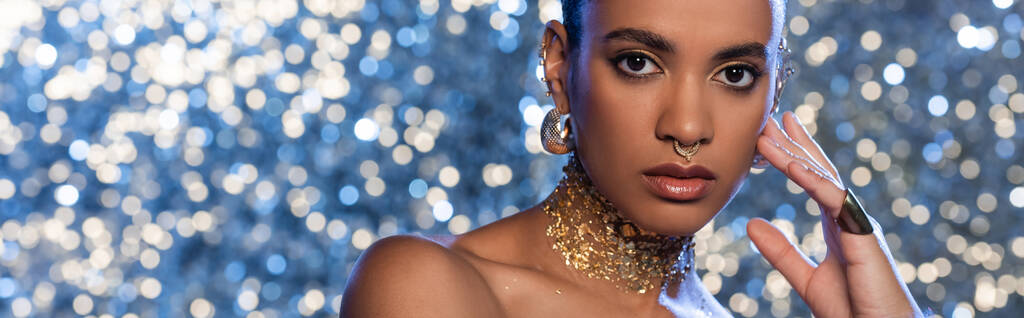 Trendy modello afroamericano in accessori dorati su sfondo blu scintillante, banner  - Foto, immagini