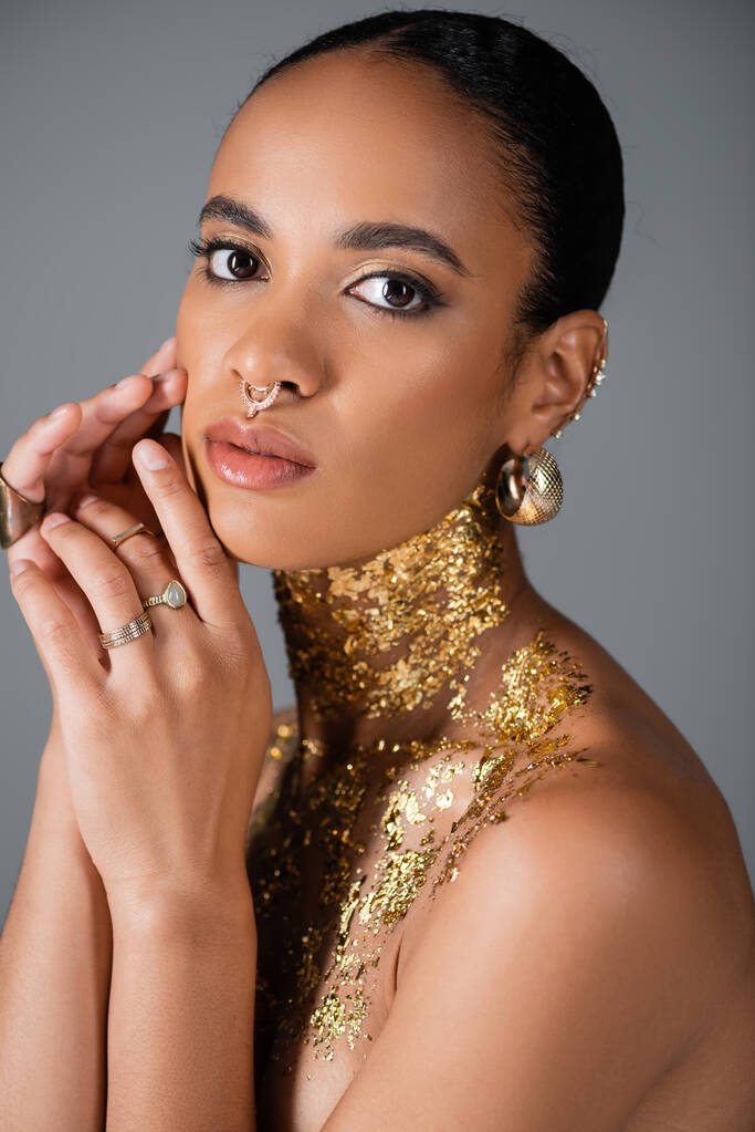 Ritratto di elegante modello afroamericano con accessori e lamina dorata sul petto isolato su grigio  - Foto, immagini
