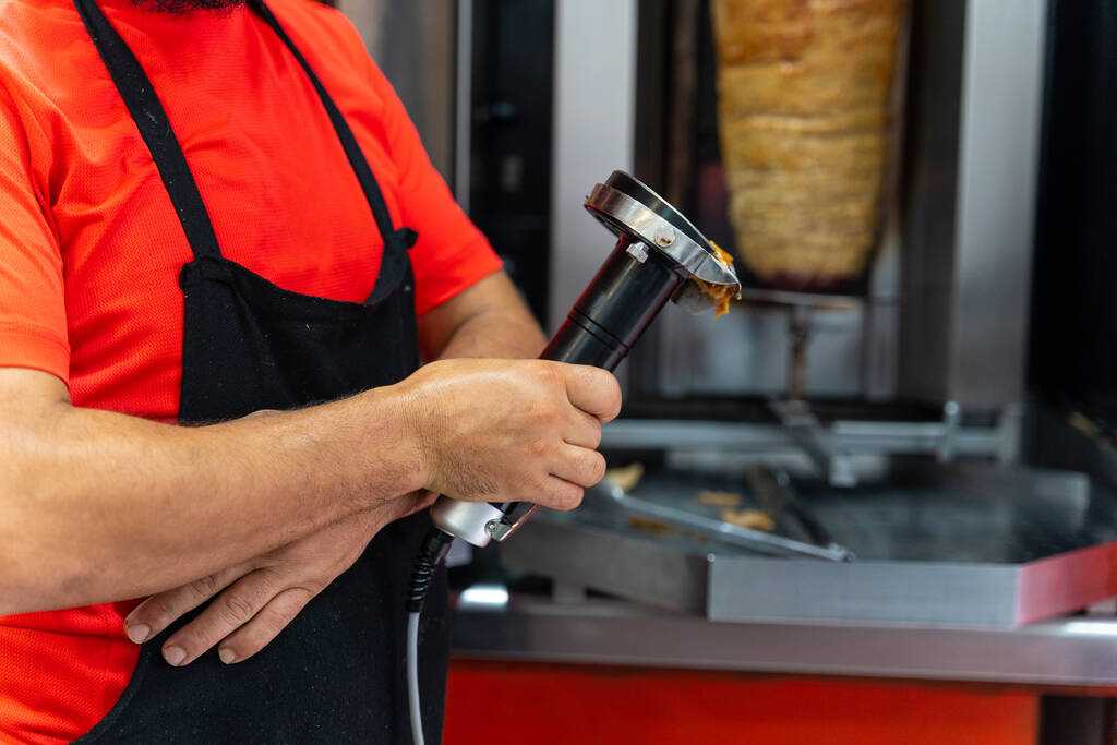 Chef du restaurant kebab, à l'aide de l'outil électrique pour couper la viande du donateur du gril - Photo, image