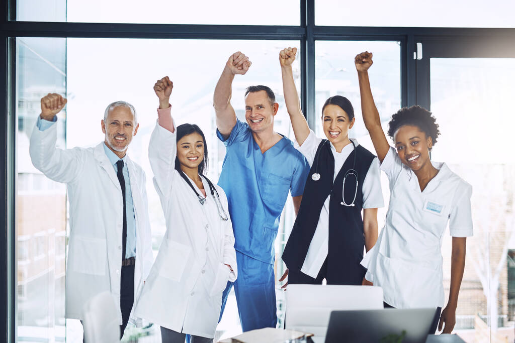To kolejne życie ocalone. Portret grupy lekarzy stojącej z podniesionymi rękami w sali konferencyjnej. - Zdjęcie, obraz