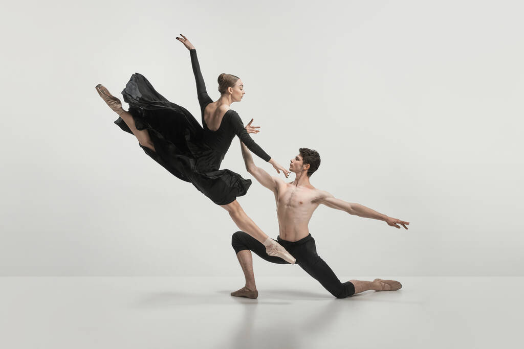Young man and woman, ballet dancers performing isolated over grey studio background. Twine jump. Concept of classical dance aesthetics, choreography, art, beauty. Copy space for ad - Photo, Image