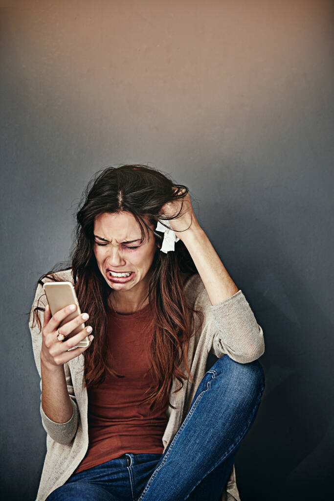 Щось треба зробити. побита і забита молода жінка плаче, дивлячись на свій мобільний телефон
 - Фото, зображення