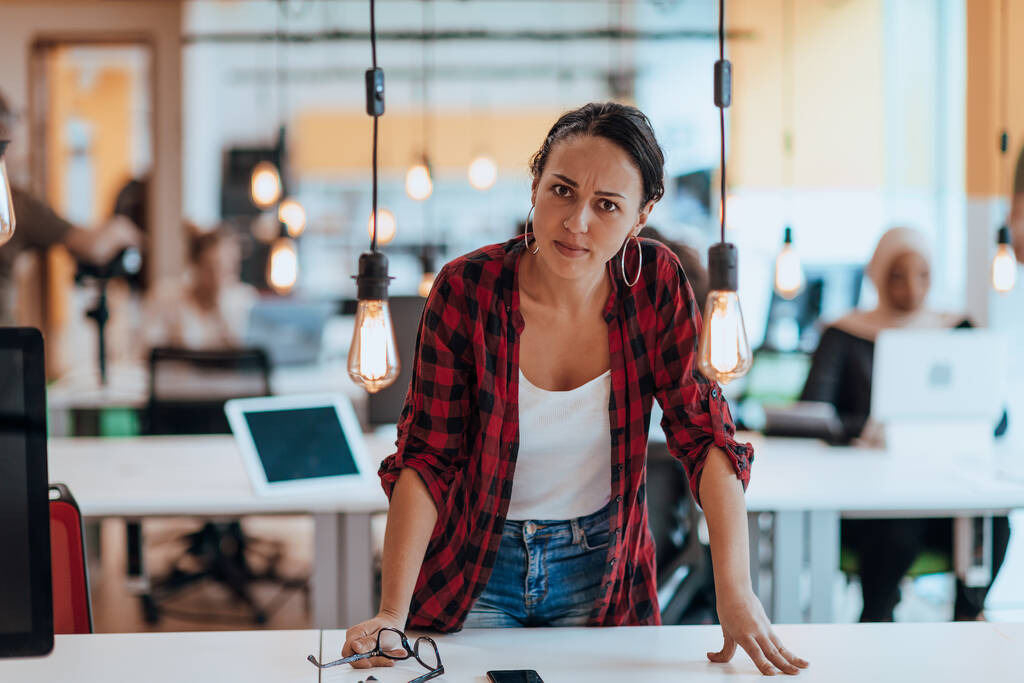 Naispuolinen pomo, johtaja, joka poseeraa nykyaikaisessa startup-toimistossa ollessaan työkavereidensa ympäröimänä, tiimi - Valokuva, kuva