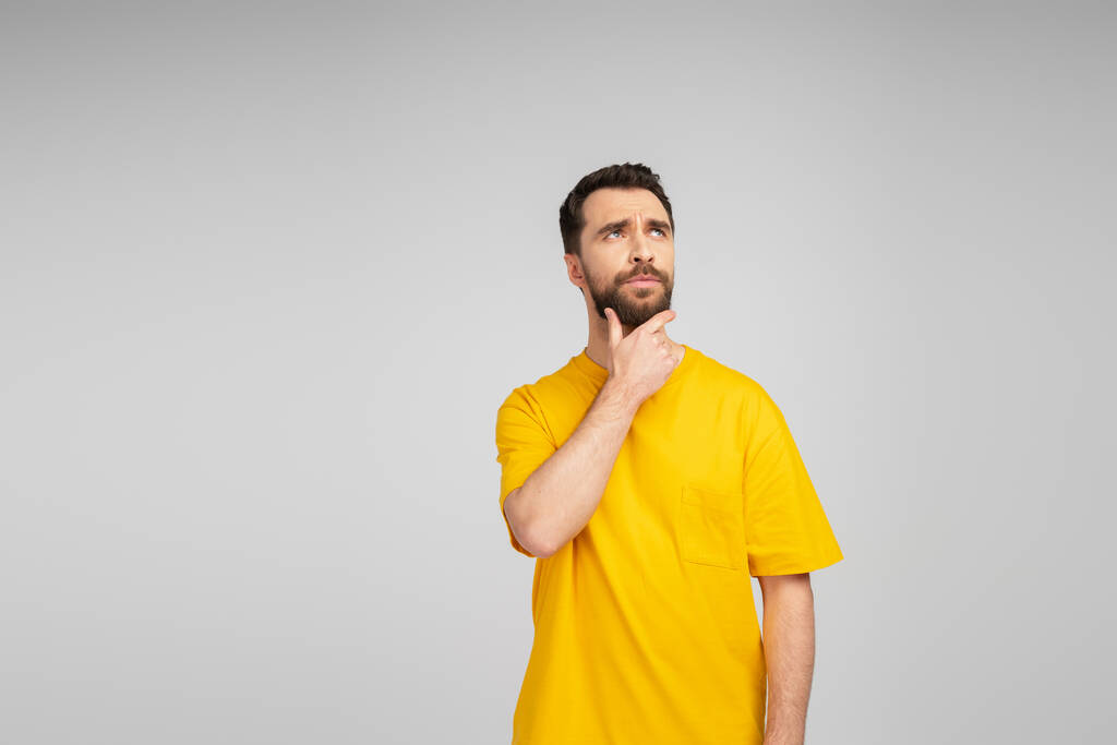 töprengő férfi sárga pólóban megható szakáll és eltekintve a szürke - Fotó, kép