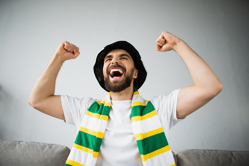 збуджений чоловік у фан-капелюсі і стиснутий шарф святкування під час перегляду чемпіонату
  - Фото, зображення