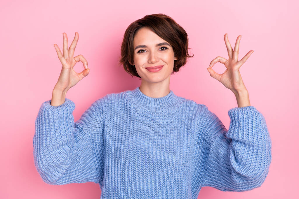 Retrato de persona bastante positiva dos dedos de los brazos hacen símbolo okey aislado en el fondo de color rosa. - Foto, imagen