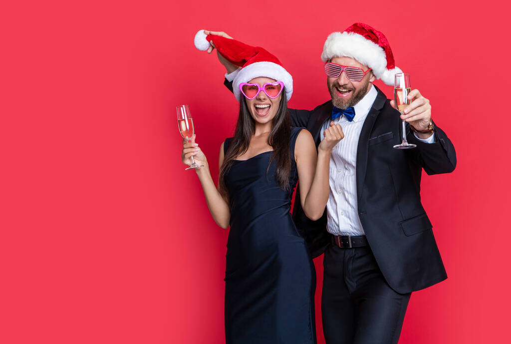 couple celebrate christmas and have fun. lets celebrate holiday. christmas couple celebrate with champagne isolated on red. celebrate christmas party with couple. merry christmas to couple in studio. - Photo, Image