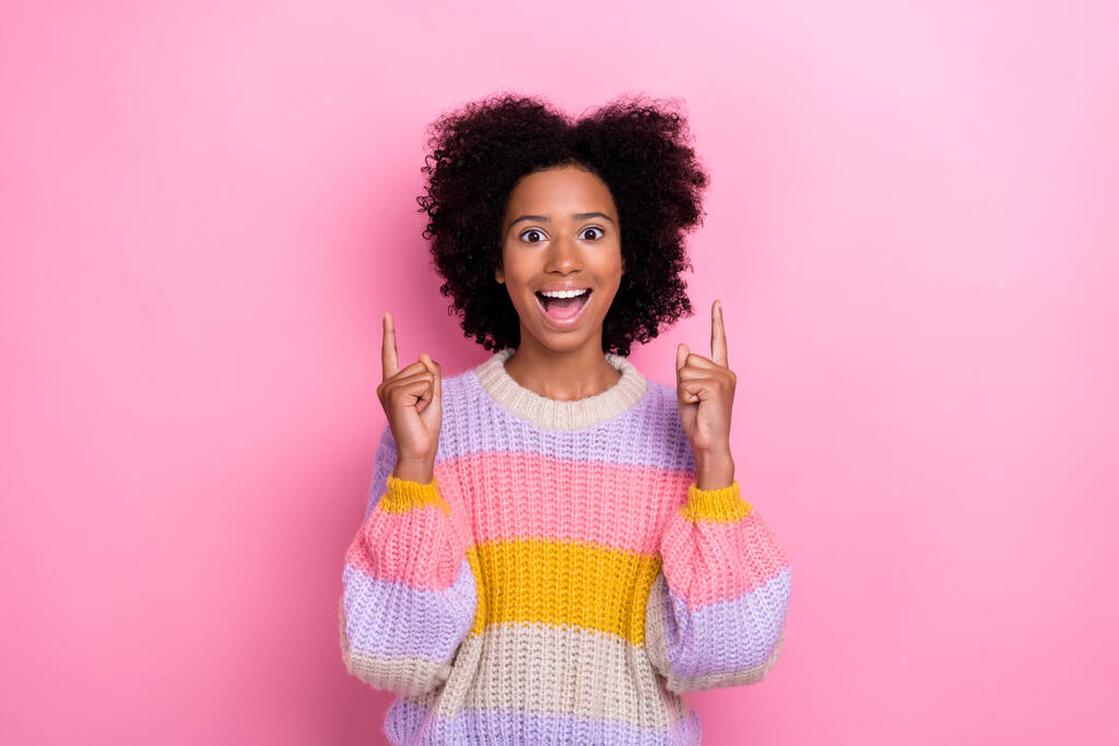 Портрет враженої екстатичної дівчини хвилястої зачіски в'язаний светр, що вказує на порожній простір ізольовано на рожевому кольоровому фоні
. - Фото, зображення