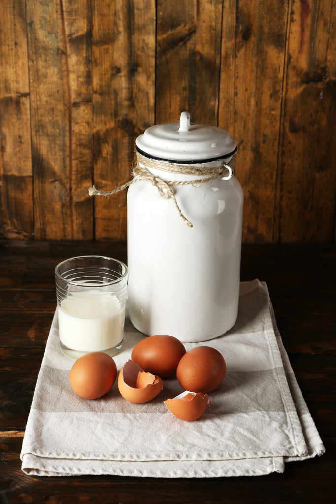 lattina di latte con uova, guscio d'uovo e vetro su sfondo in legno rustico
 - Foto, immagini
