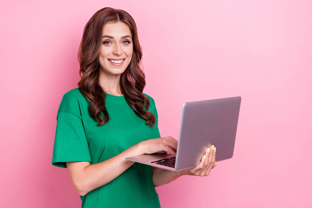 Портрет милой красивой женщины хорошего настроения с волнистой прической носить зеленую футболку написания электронной почты на ноутбуке изолированы на розовом фоне цвета. - Фото, изображение