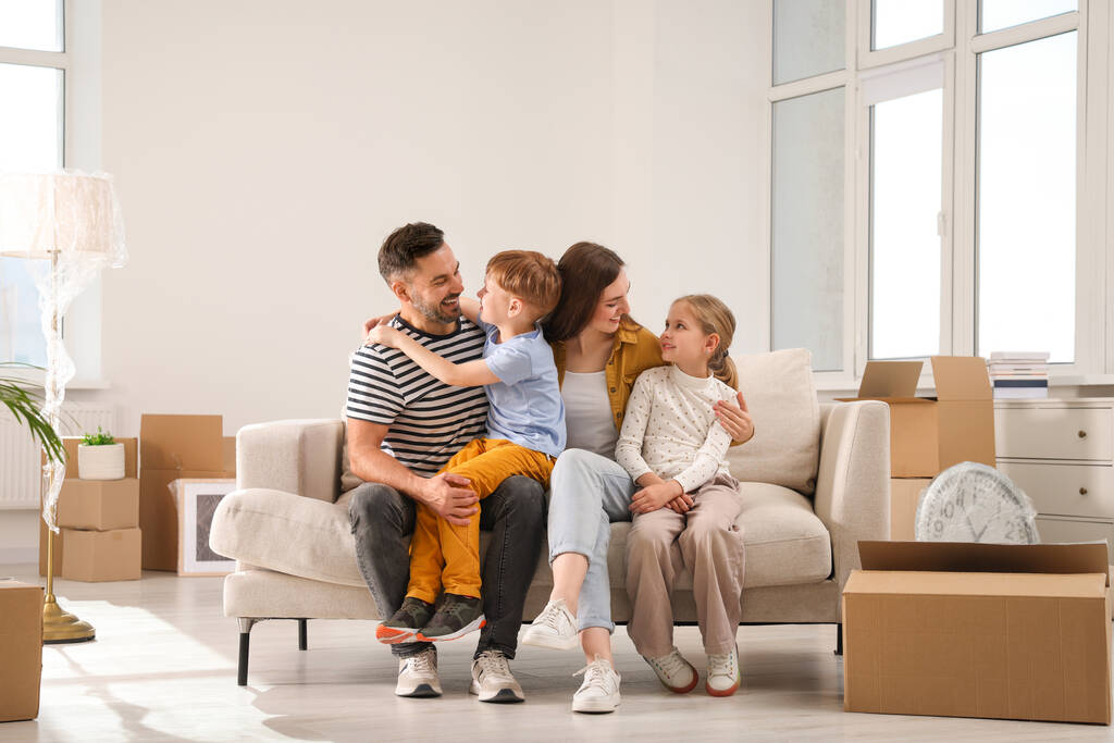 幸せな家族は新しいアパートのソファに座っています。移動日 - 写真・画像