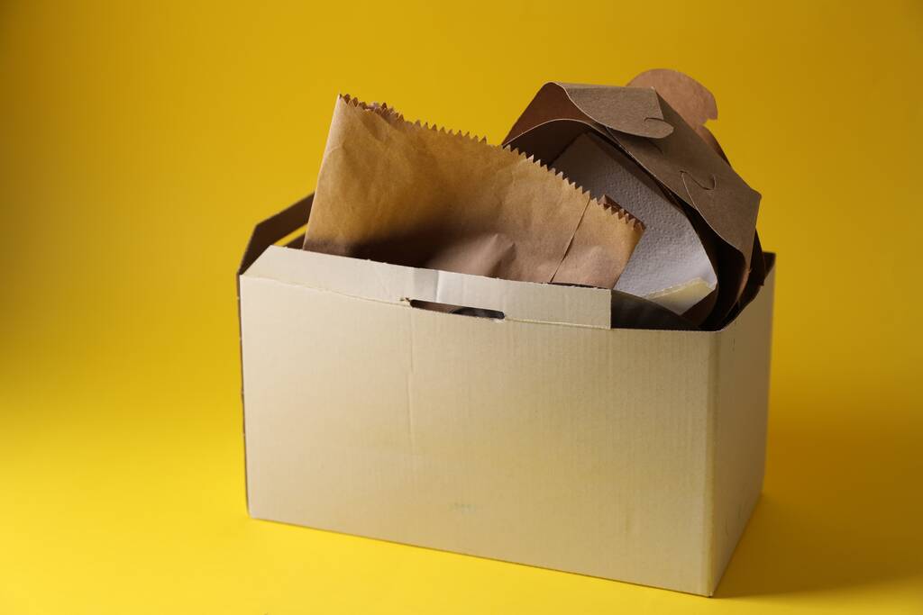 Boîte avec des déchets de papier sur fond jaune - Photo, image