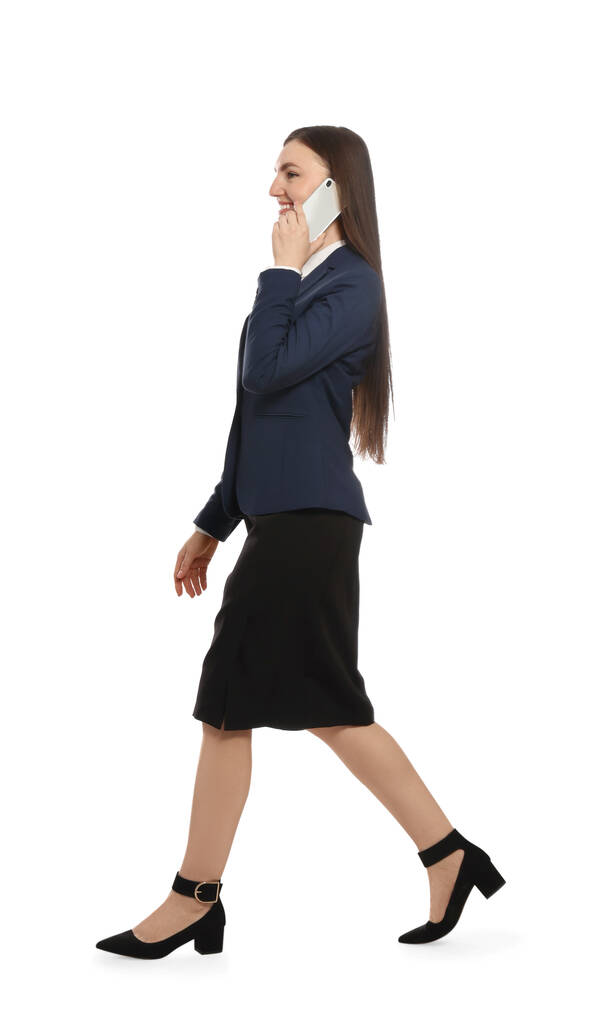 Молодая деловая женщина разговаривает по смартфону, идя на белом фоне - Фото, изображение