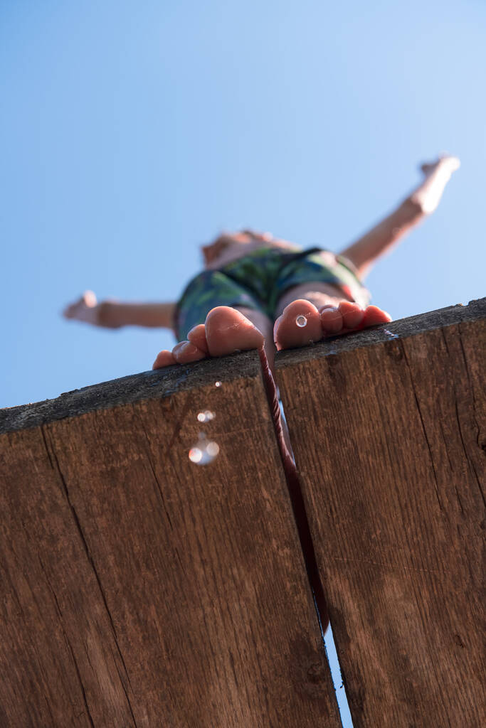 mladý muž se připravuje skočit do vody čisté řeky, plave, rád tráví čas na letních prázdninách. Kvalitní fotografie - Fotografie, Obrázek