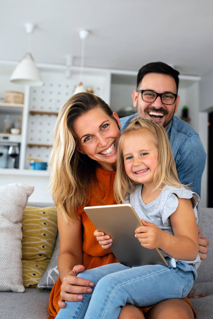 Ευτυχής οικογένεια ξοδεύουν χρόνο στο σπίτι και χρησιμοποιώντας ψηφιακή συσκευή μαζί. Τεχνολογία άνθρωποι διασκέδαση έννοια. - Φωτογραφία, εικόνα